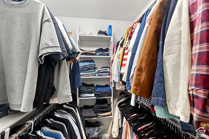 Walk-in closet featuring dual-level metal hanging rods and white built-in shelving
