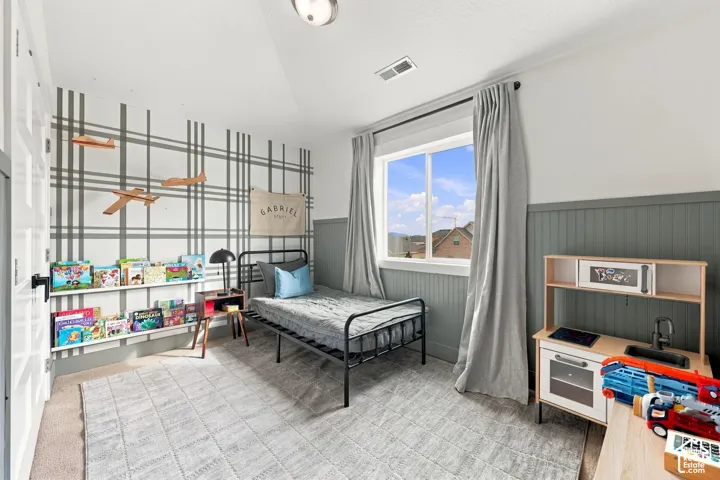 Room featuring vaulted ceilings, floor-to-ceiling wainscoting, a wall-mounted floating display shelf, and a large sliding window with mountain scenery