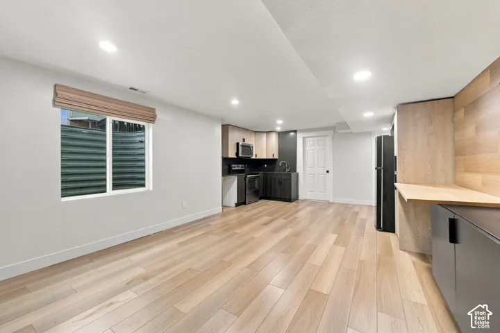 Kitchenette featuring flat-panel cabinetry, wood-finish wall paneling, recessed lighting, and wood-finish flooring