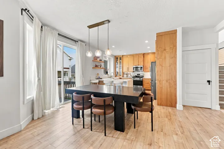 Kitchen featuring wood-finish cabinetry, built-in pantry, sliding glass door, recessed lighting, and a triple-pendant light fixture over the designated eating area