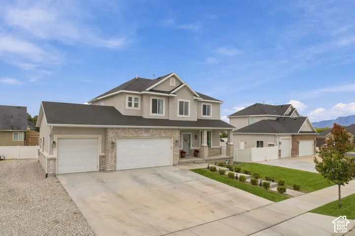 Two-story residence featuring a composite shingle roof, stone veneer accents, three-car garage, and concrete driveway
