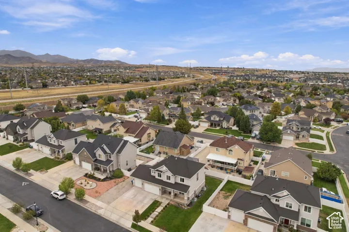 Aerial perspective featuring a multi-story residential neighborhood with paved streets, manicured lawn areas, and prominent mountain range backdrop