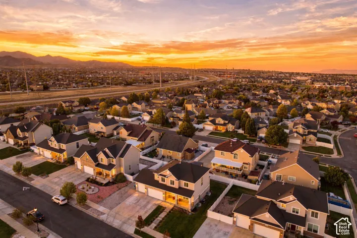 Aerial perspective featuring suburban residential development, paved streets, mountain backdrop, and golden hour sky