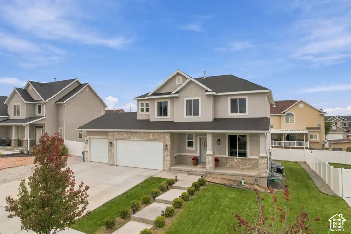Multi-level exterior featuring a stone veneer facade, a covered front porch with stone-wrapped columns, a three-car garage, and a concrete driveway