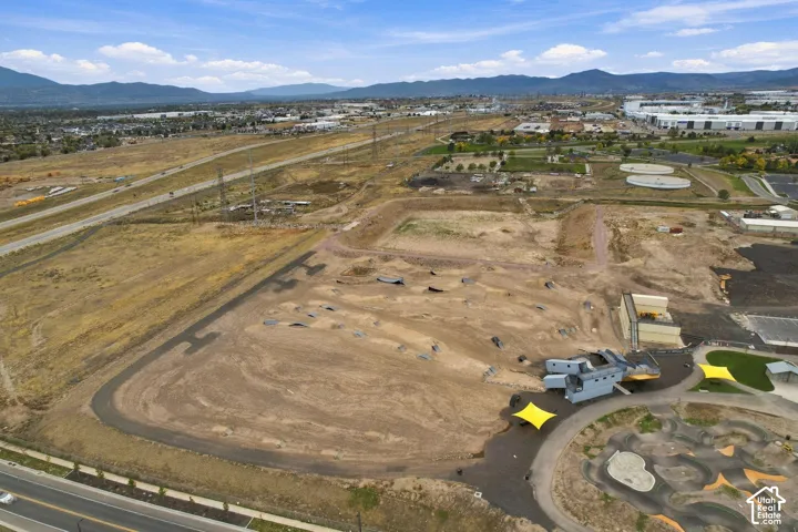 Expansive land parcel featuring an established dirt-track course, paved perimeter pathway, and mountain range backdrop