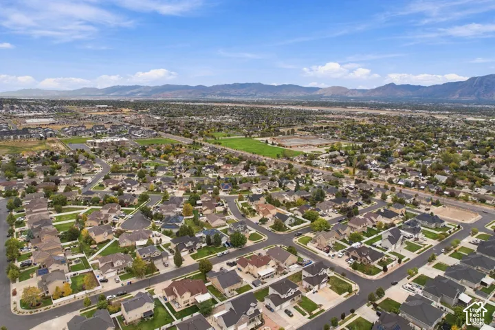 Aerial perspective of the residential area featuring paved street grids, manicured lawns, mature tree canopy, and mountainous backdrop