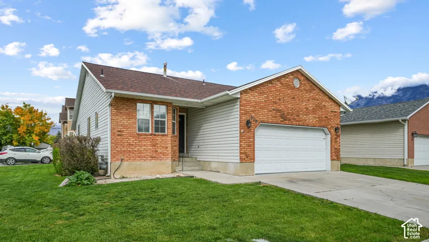 Exterior facade featuring a combination of brick masonry and horizontal siding, asphalt shingle roofing, concrete driveway, two-car garage, and mountain backdrop