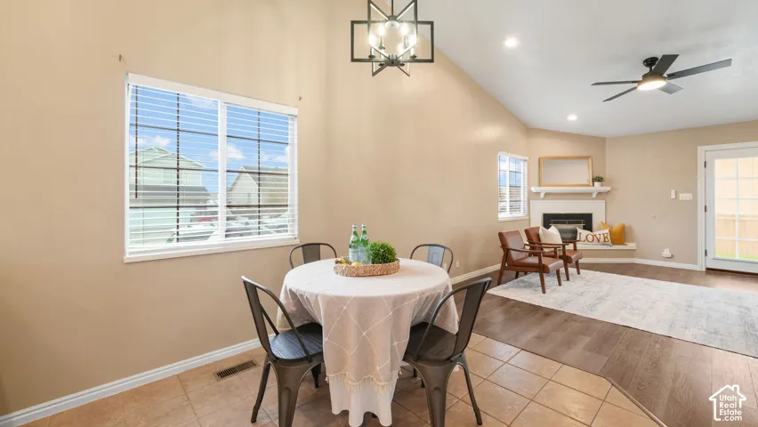 Vaulted ceiling, corner fireplace with mantel, open-plan layout, wood-finish LVP flooring, and backyard access