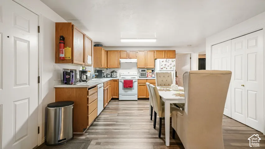 ADU Kitchen featuring wood cabinetry, white appliance suite, wood-finish flooring, and double-door closet storage