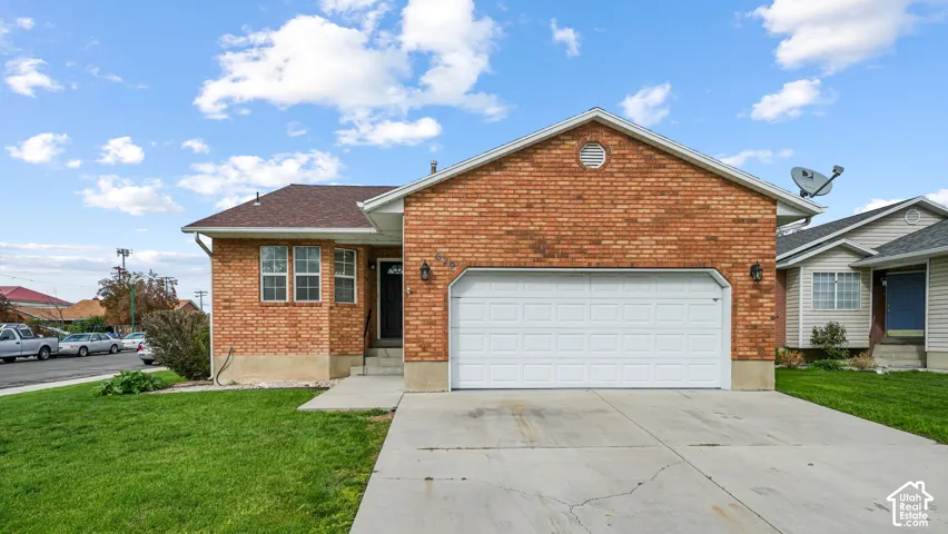 Single-story brick exterior featuring a concrete driveway, two-car garage, and asphalt shingle roof