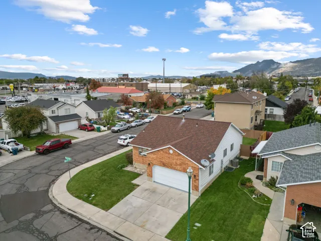 Corner lot property featuring brick and siding exterior, attached two-car garage, concrete driveway, and mountain backdrop