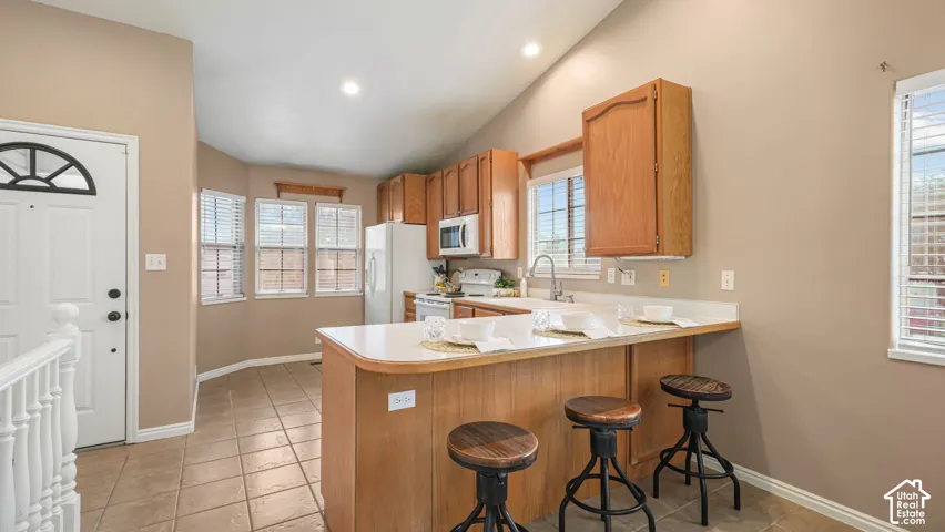 Kitchen featuring wood cabinetry, a breakfast bar with a solid surface countertop, tile flooring, and recessed ceiling lighting