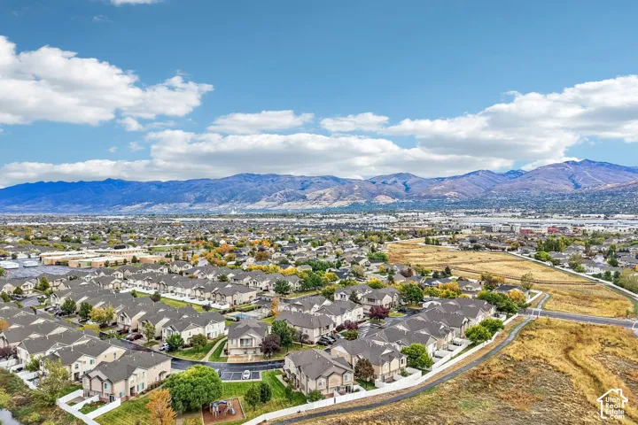 Aerial perspective of a residential community featuring multi-family dwellings, integrated paved walkways, and a backdrop of mountain ranges