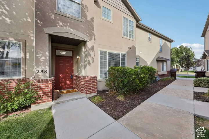 Stucco exterior with brick facade detailing, arched entryway, and concrete walkway
