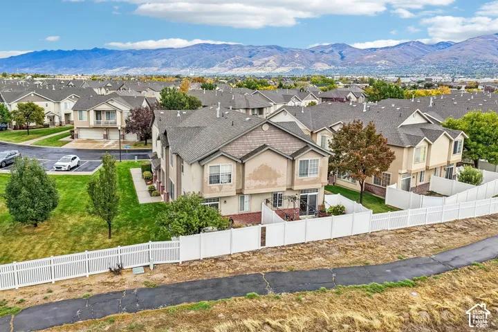 Multi-unit residential complex featuring gabled rooflines, stucco siding, private fenced rear patios, and mountain backdrops