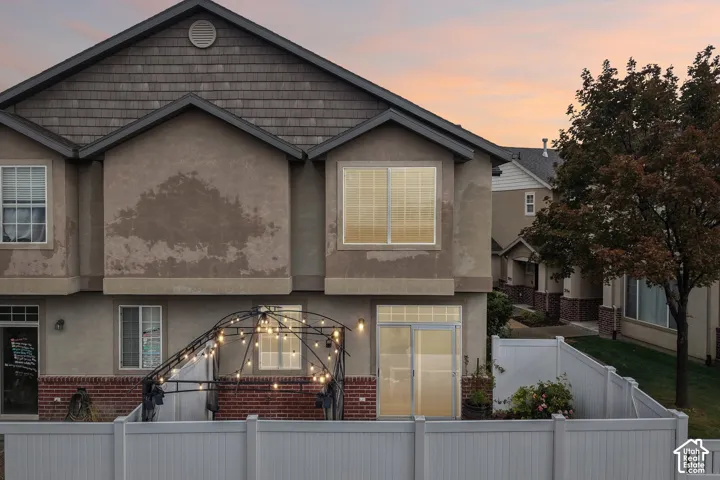 Multi-level exterior featuring stucco and brick masonry, shake-style gable detailing, and a fenced private patio