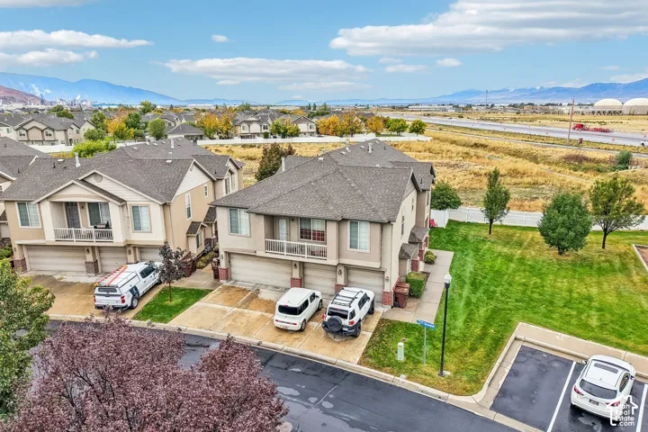 Multi-level townhome exterior featuring shingled roofing, neutral-toned siding, stone-accented masonry, an attached two-car garage, and a second-level balcony