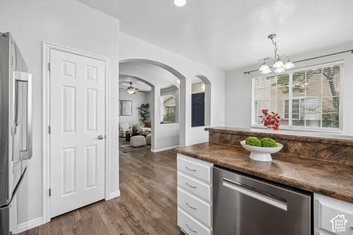 Kitchen featuring white cabinetry, stone-finish countertops, stainless steel appliances, recessed ceiling lighting, and wood-finish flooring with arched architectural detailing