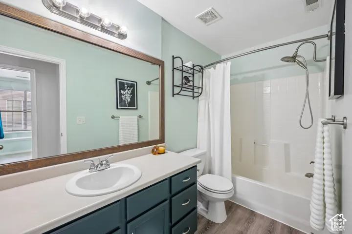Bathroom featuring a vanity with a solid-surface countertop, an oversized wall mirror with a wood frame, dark-toned cabinetry, and a shower-tub combination with a handheld fixture