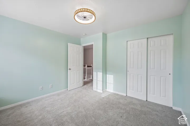 Neutral-toned carpeting, dual-panel closet doors, and circular integrated ceiling lighting fixture