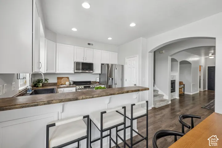 Kitchen featuring white shaker-style cabinetry, breakfast bar, recessed lighting, and stainless steel appliances