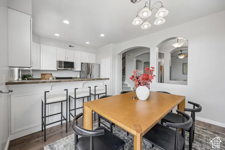 Kitchen featuring white shaker cabinetry, a breakfast bar with stone-finish countertop, stainless steel appliances, recessed lighting, and a multi-bulb chandelier
