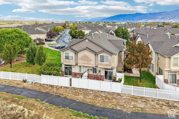 Two-story exterior featuring a shingle roof, dual sliding glass doors, brick masonry base, and a white vinyl privacy fence