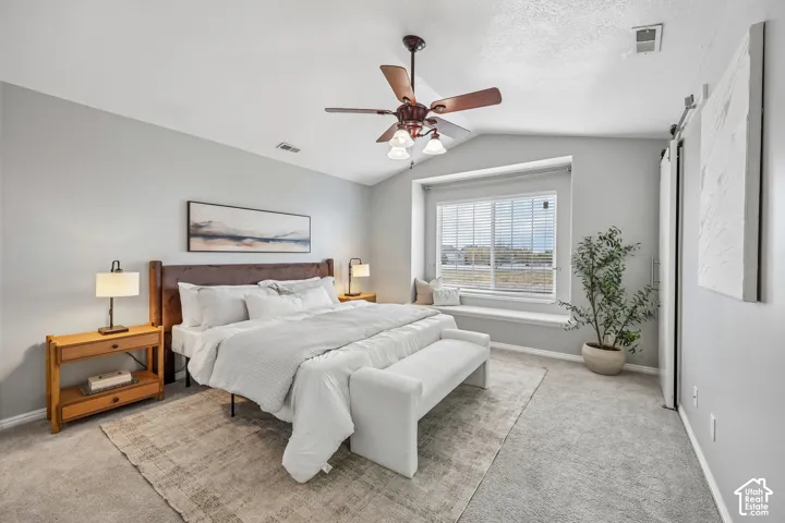 Vaulted ceilings featuring a central overhead fan, a built-in window bench, and a sliding door
