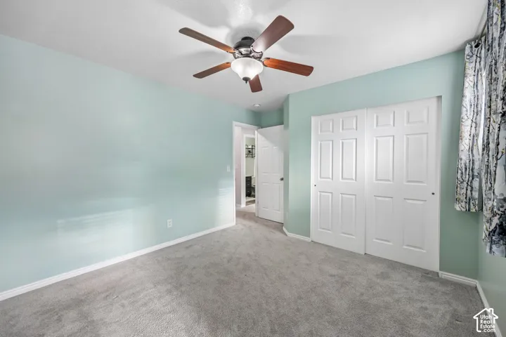 Neutral-toned carpeting, ceiling-mounted fan with integrated lighting, and multi-panel interior doors with white finish