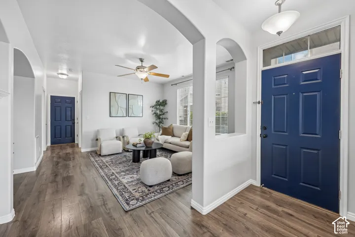 Entryway featuring wood-finish flooring, a bold navy blue paneled front door with a transom window, arched wall cutouts, and a ceiling-mounted light fixture