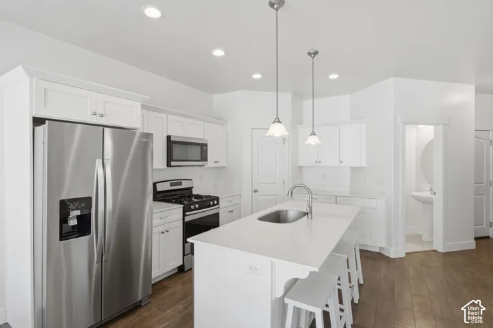 Kitchen featuring stainless steel appliances, white cabinetry, a kitchen island with an undermount sink, and recessed lighting