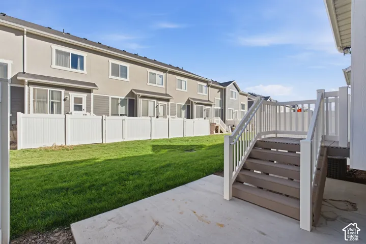 Private fenced yard with concrete patio and deck featuring white railings