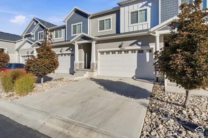 Multi-unit property featuring a concrete driveway, attached garage, and stone facade accents