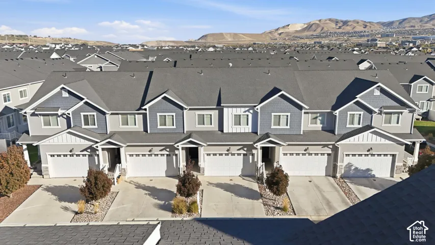 Multi-story townhomes with attached garages, individual driveways, and mountain scenery