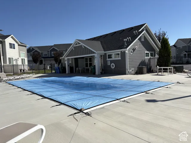 Outdoor swimming pool with a protective cover, concrete decking, and covered patio structure