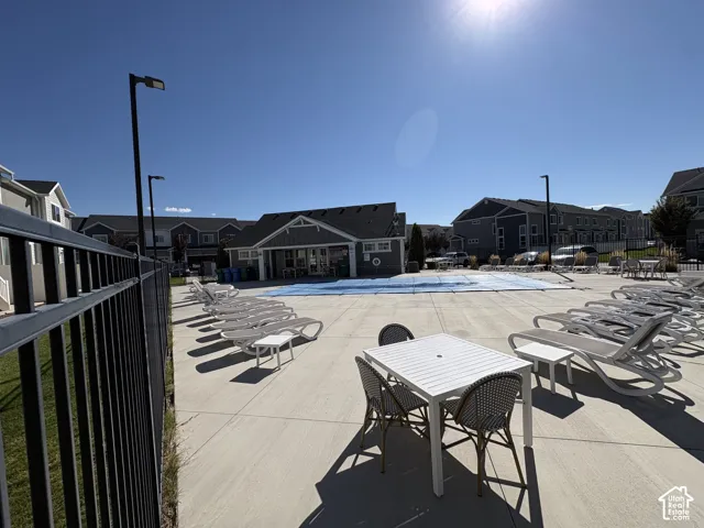 Swimming pool area featuring a concrete deck, metal perimeter fencing, and a clubhouse structure