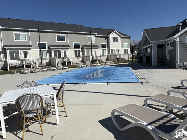 Community swimming pool with concrete decking, perimeter metal fencing, and multi-story residential structures