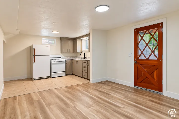 Wood-finish flooring, tiled kitchen workspace, shaker-style cabinetry, and an exterior door featuring a diamond-pattern light