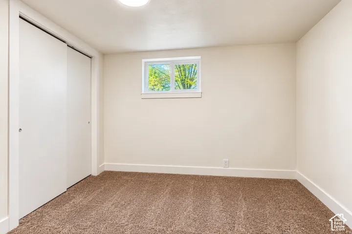 Neutral-toned wall paint, wall-to-wall carpeting, sliding-door closet, and a single-pane slider window