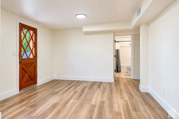 Room featuring wood-finish flooring, a natural wood door with a diamond-pattern window, and a flush-mount circular ceiling light