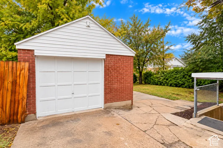 Detached garage featuring red brick exterior, white horizontal siding, and a single-car overhead door