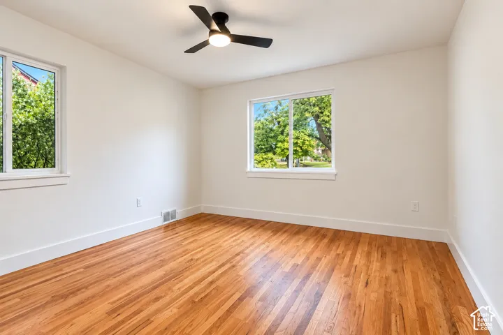 Room 1  featuring wood-finish flooring, dual windows, and a ceiling-mounted light fixture with fan blades