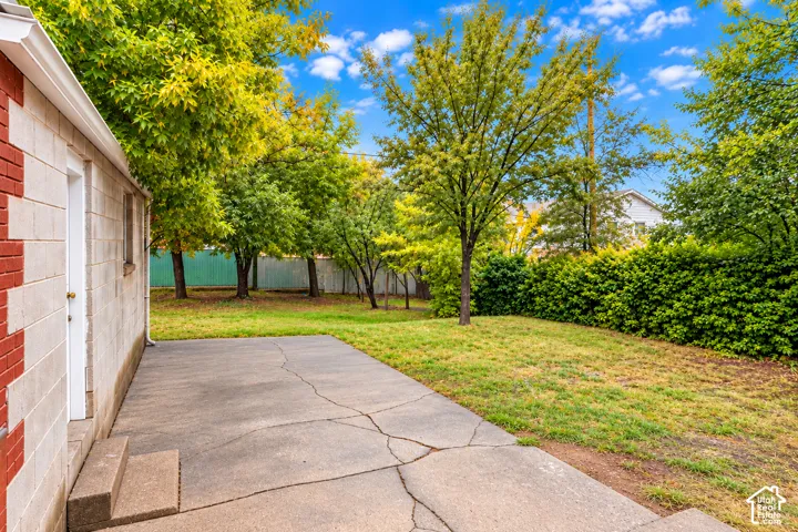 Concrete patio exterior featuring a brick and concrete block facade, expansive lawn, and mature trees