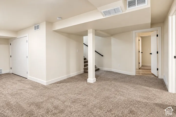Neutral-toned interior space featuring wall-to-wall carpeting, painted solid-core doors, and a structural support column