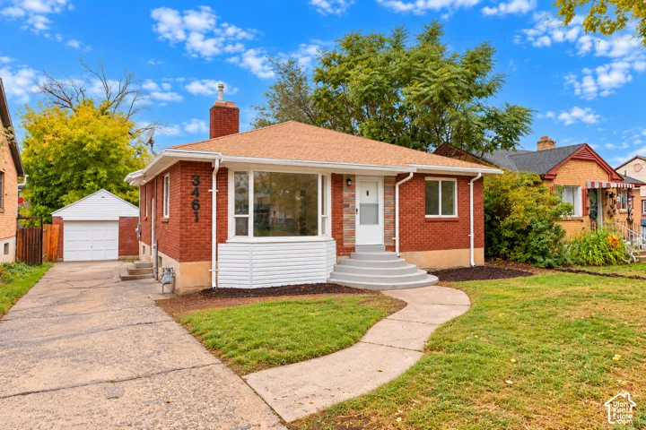 Red brick exterior with white siding accents, bay window, concrete front steps, and a detached single-car garage