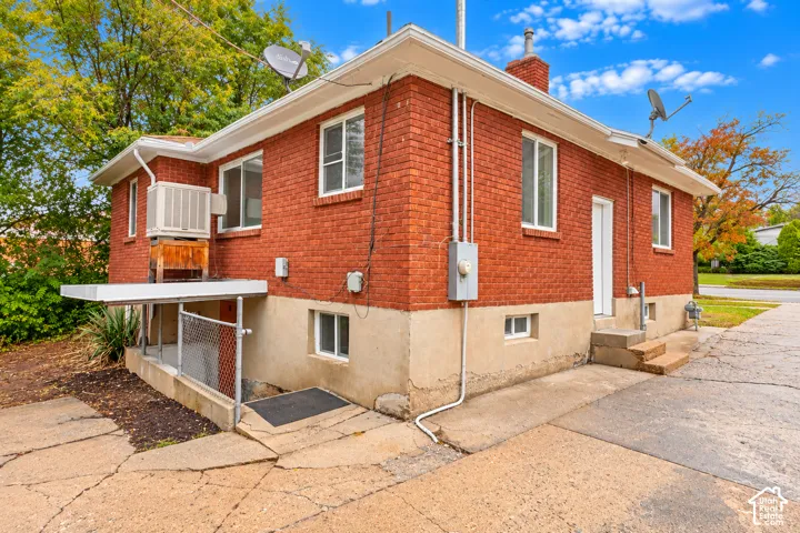 Red brick exterior featuring white-framed windows, a concrete foundation, and a concrete driveway
