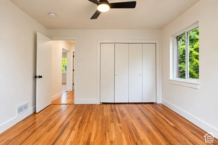 Room 1 featuring wood-finish flooring, a bi-fold closet, a ceiling-mounted light fixture, and a dual-pane window