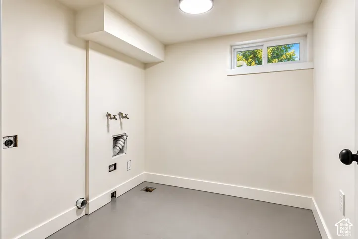 Dedicated utility space featuring neutral wall paint, smooth flooring, recessed laundry connections, and a horizontal sliding window