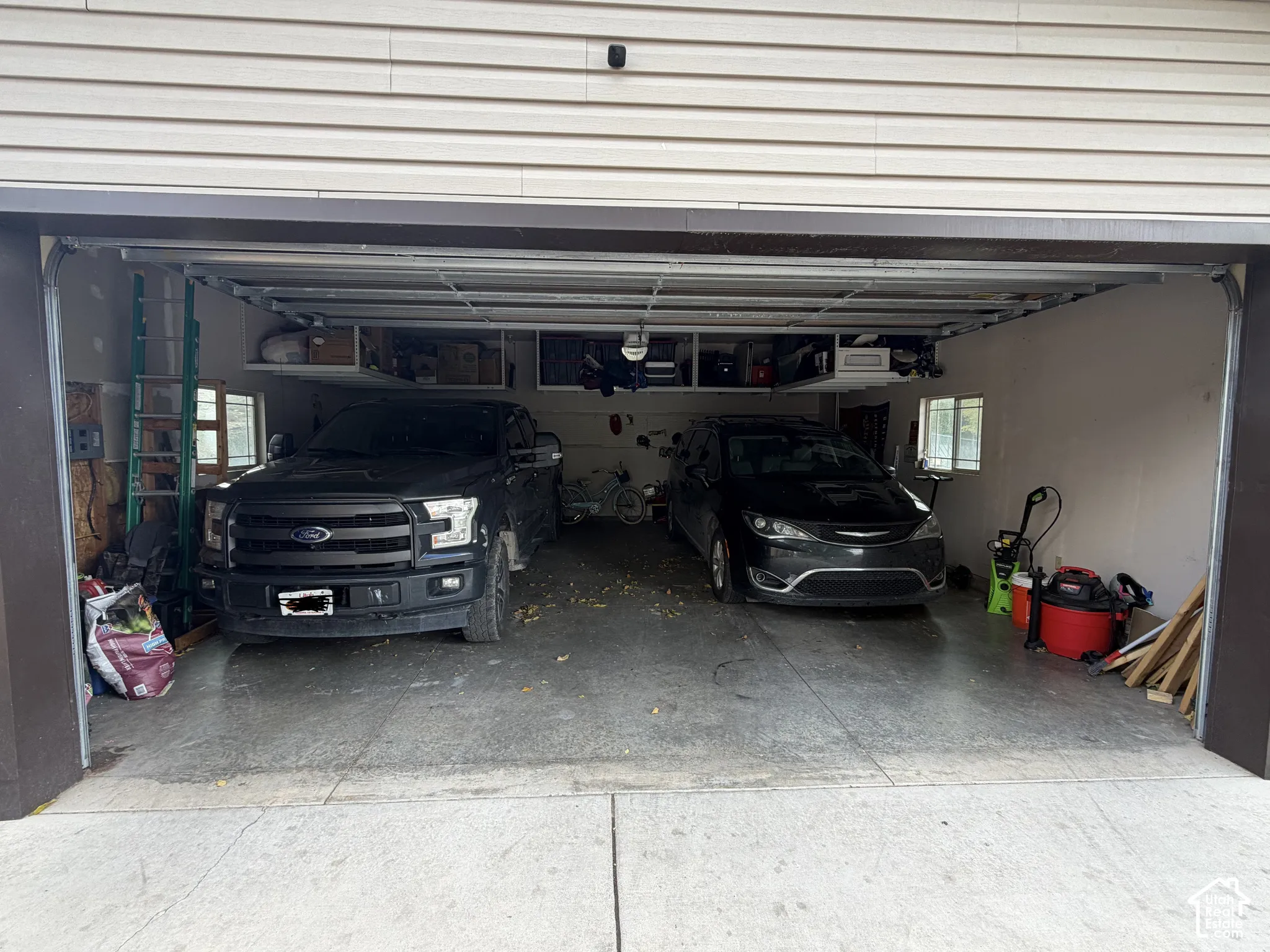 Two-car garage featuring a concrete floor, built-in overhead storage shelving, and dual windows