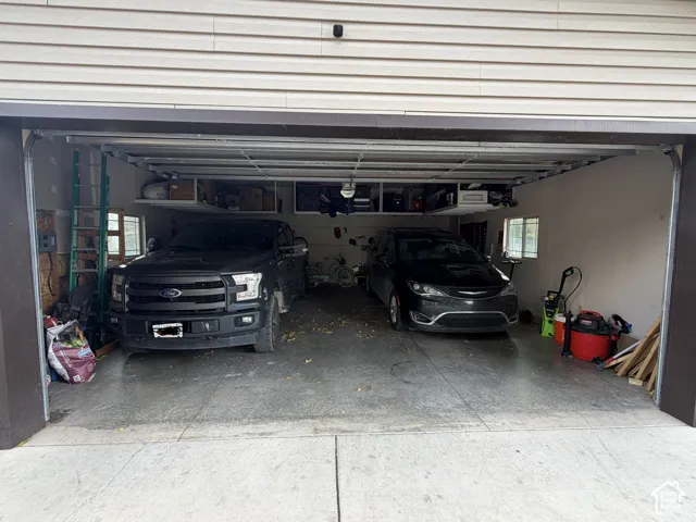 Two-car garage featuring a concrete floor, built-in overhead storage shelving, and dual windows